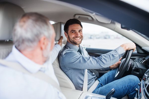 Mann zeigt auf die Kopfstütze, während ein Fahrer am Steuer eines Autos sitzt.